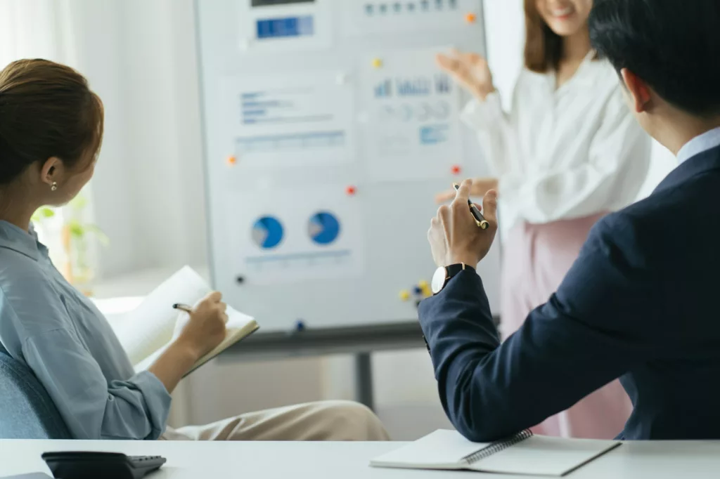Three colleagues are concentrated on data at the flipchart, disscussing the solutions of their comp